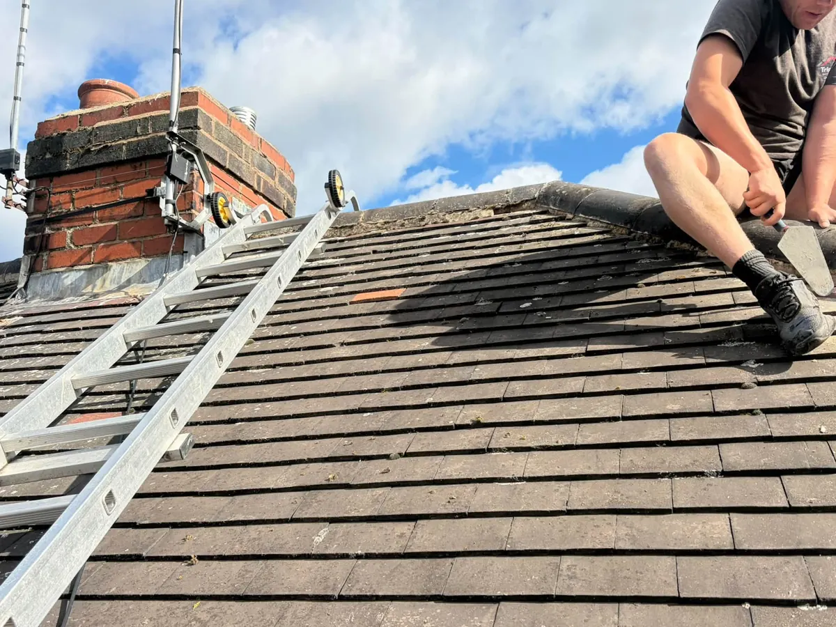 Roofer working on ridge tiles of a pitched roof
